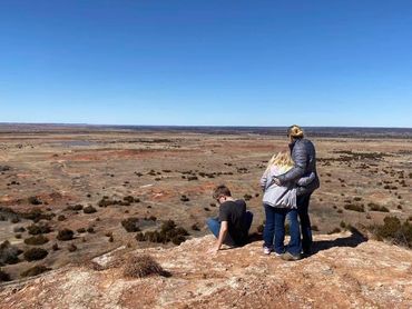 mother and two children a boy and a girl on a rock ledge viewing terrain during homeschooling trip