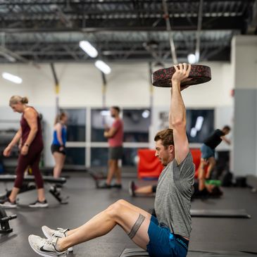 Athlete performing an overhead plate press at Titan