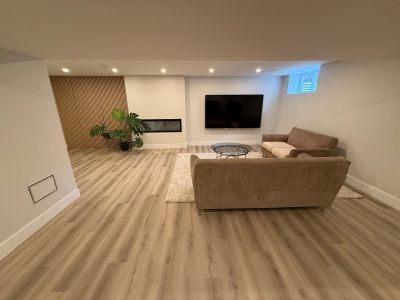 Modern living room with beige sofas, a wall-mounted TV, and a fireplace.