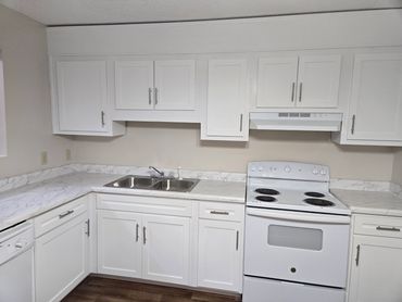 Clean white kitchen with marble countertops and modern appliances.