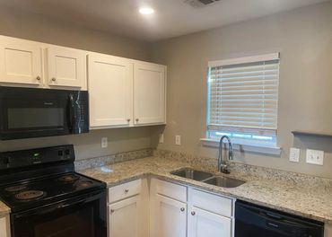 Modern kitchen with black appliances and granite countertops.