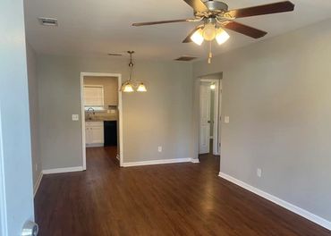 Empty room with wooden floor and ceiling fan.