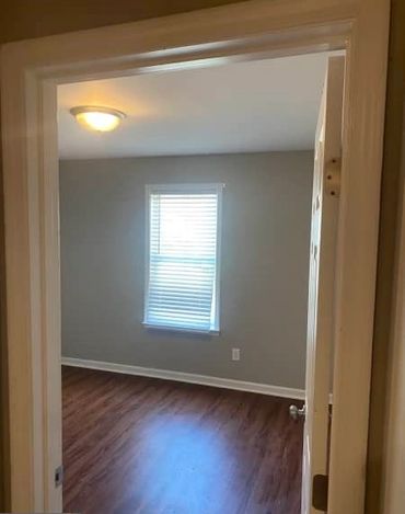 Empty room with wooden floor and window blinds.