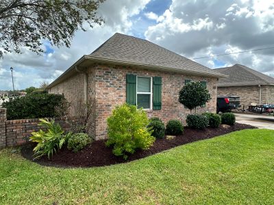 Landscape bed with shrubs and dark mulch at a Lake Charles brick home by Lawson Landscaping