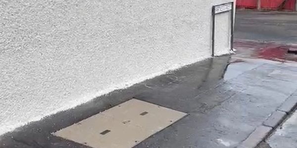 A street corner with a beige utility cover and a signpost.