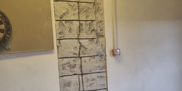 Stone wall section inside a plain room.