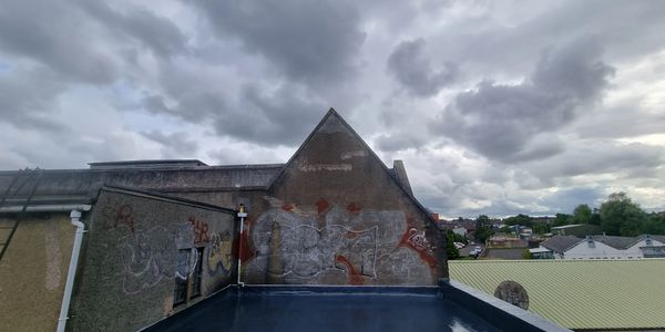 Graffiti on the side of a building under a cloudy sky.