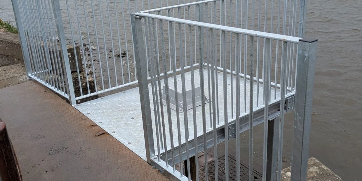 Metal platform with railings above water.