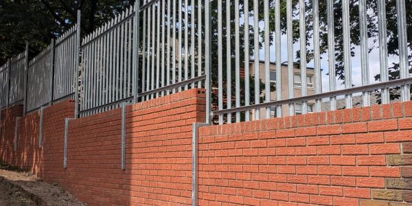 Brick wall with metal fencing on top.