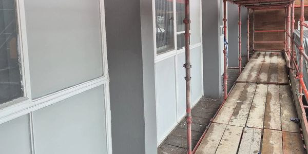 Scaffolding next to a grey building wall.