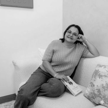 Mujer sonriente leyendo en el sofá.
