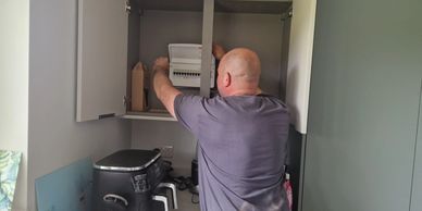 Man organizing items in kitchen cabinet.