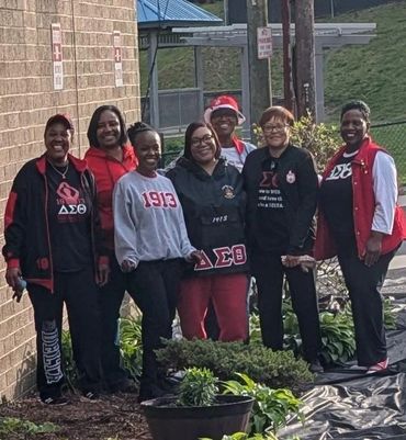 Group of women in Delta Sigma Theta sorority apparel outdoors.