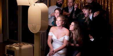 A group of friends happily taking a photo at a party with a photo booth.