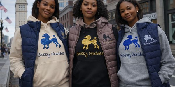 Three women wearing hoodies and vests with 'Bossy Goddess' and poodle designs.