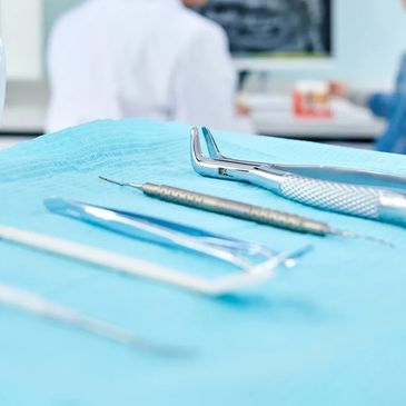 Dental tools arranged on a blue cloth in a clinic setting.