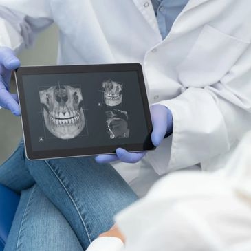 Doctor showing a dental X-ray on a tablet to a patient.