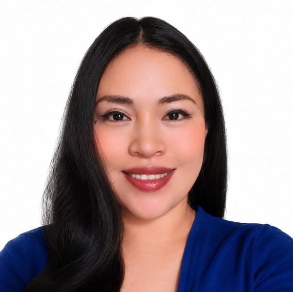 Mujer sonriente con cabello largo y camisa azul.