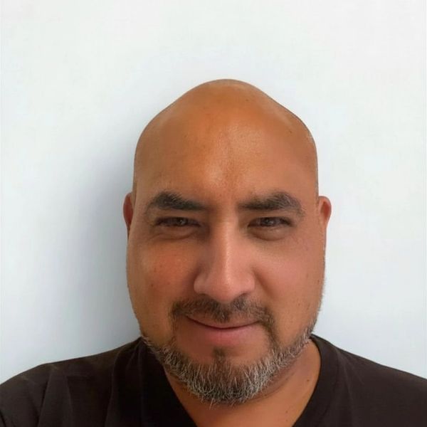 Hombre calvo con barba corta y camiseta negra.