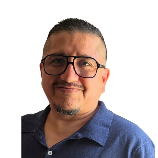 Hombre sonriente con gafas y camisa azul.