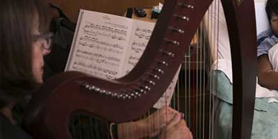 Certified Music Practitioner playing  Live Therapeutic Music on a harp for a patient