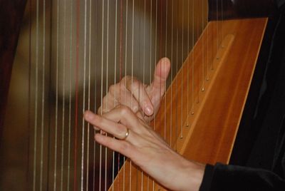 Hands playing a harp, which is a common instrument used for Live Therapeutic Music
