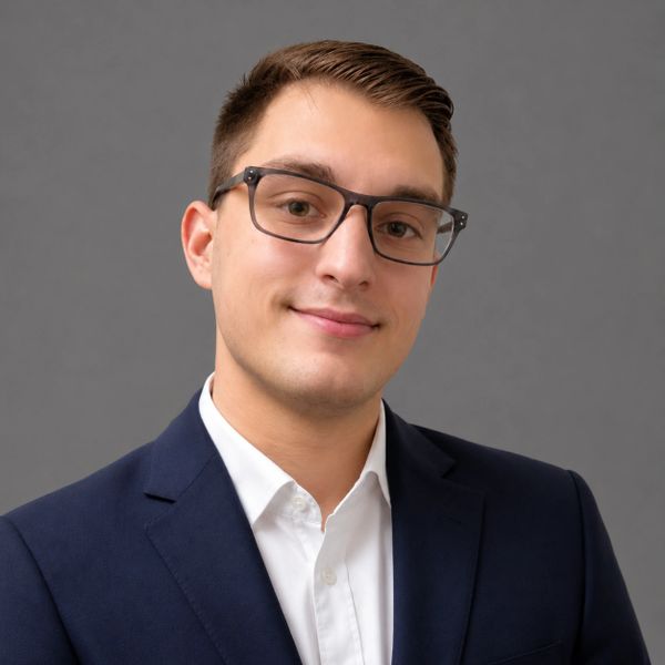 Young man in glasses and business suit smiling at camera.