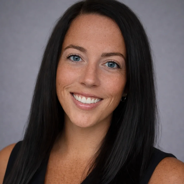 Smiling woman with long black hair and blue eyes in a sleeveless top.