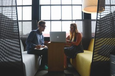 Two people work together on a laptop in a modern office space.