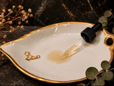 Dropper on leaf-shaped ceramic dish with liquid.