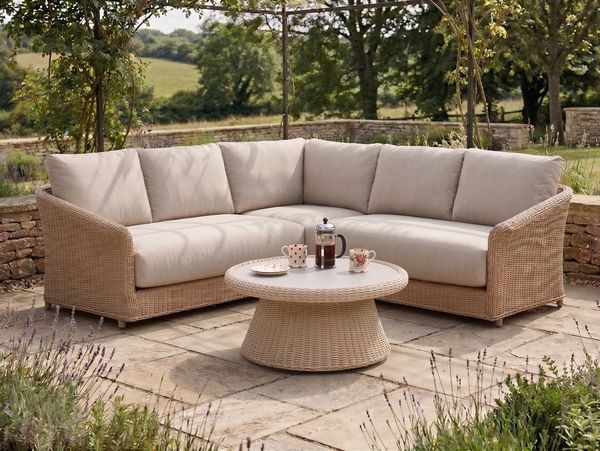Outdoor wicker sectional sofa with beige cushions and a matching round coffee table.
