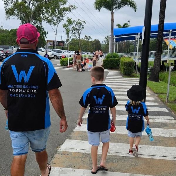 Three people wearing matching shirts crossing a street.