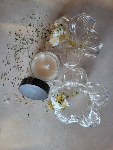 Glass flower-shaped containers with cream and herbs on a table.