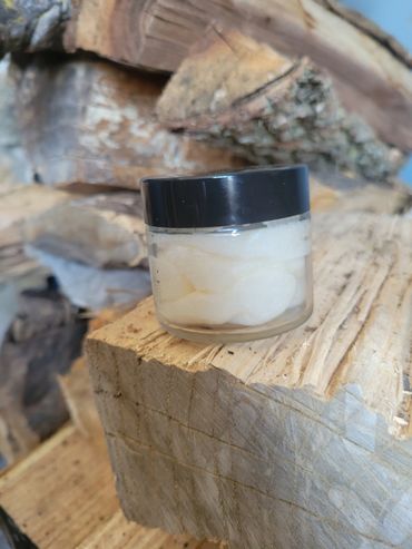 Small jar of cream on stacked firewood.