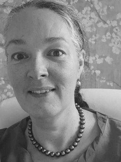 Black and white portrait of a woman wearing a pearl necklace and earrings.