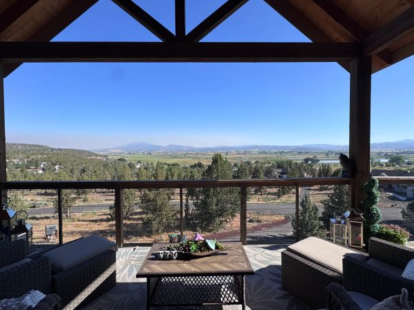 Covered patio with furniture overlooking a scenic valley and distant mountains.