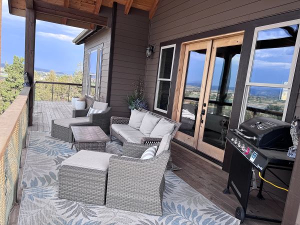 Cozy outdoor patio with wicker furniture and scenic mountain views.