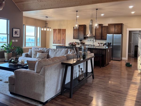 Cozy open living room and kitchen with wooden ceiling and mounted animal heads.