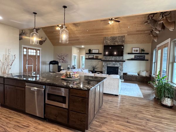Rustic open-concept living room and kitchen with wooden accents and mounted deer heads.