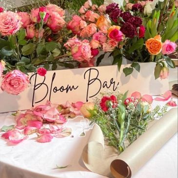 A vibrant flower bar with assorted roses and greenery ready for bouquet making.
