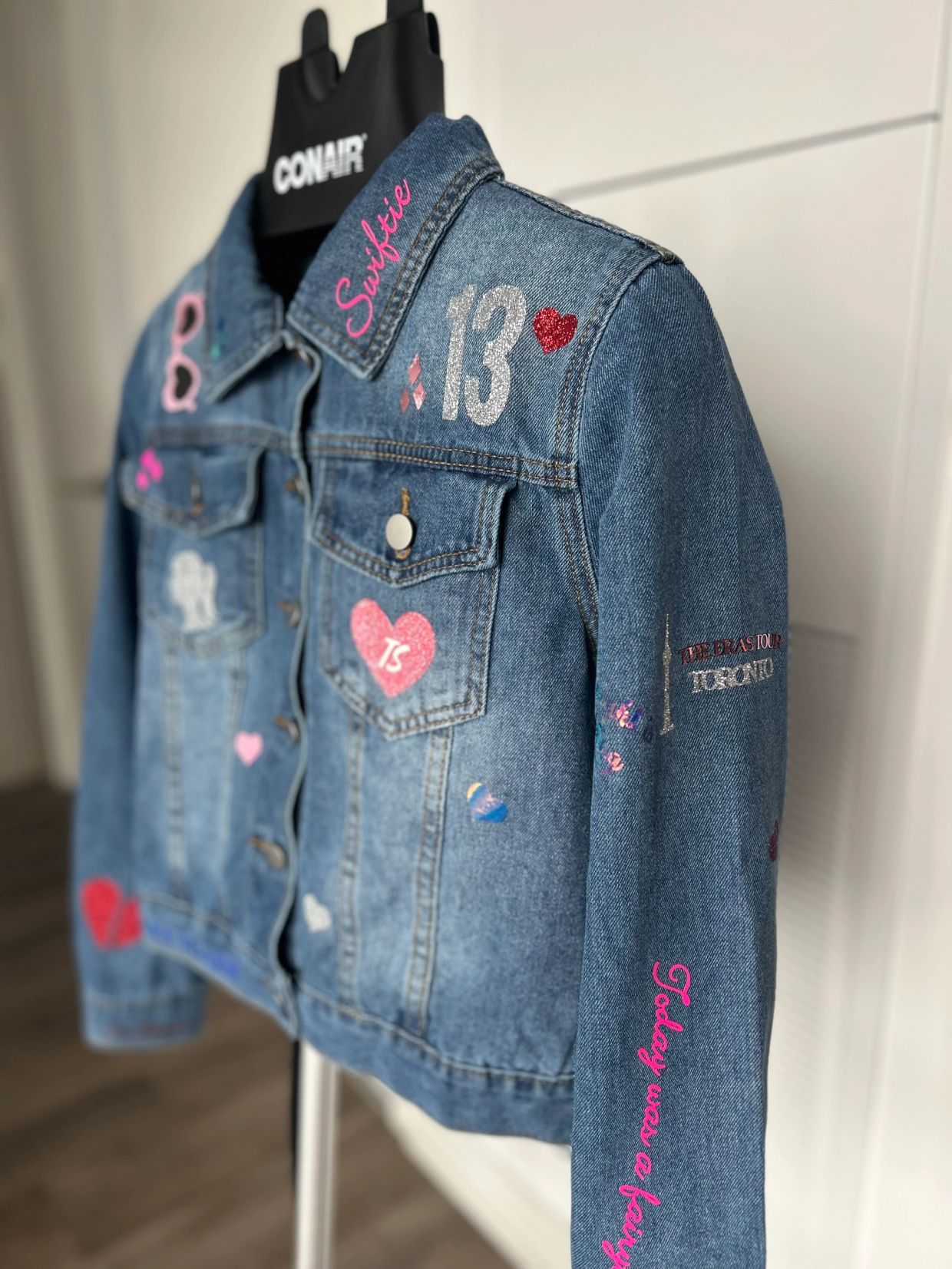 Denim jacket with colorful patches and "Swiftie" text on collar.