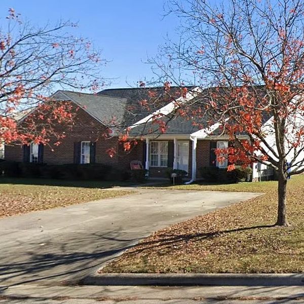 Brick house with autumn trees and empty driveway.