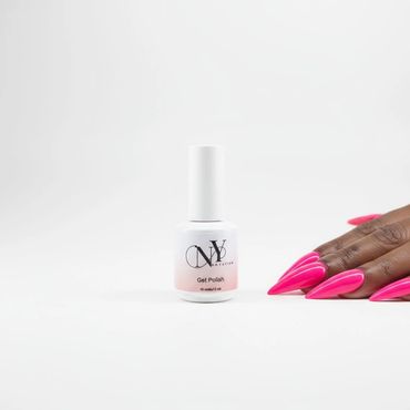 Bright pink long stiletto nails next to a white nail polish bottle on a white background.