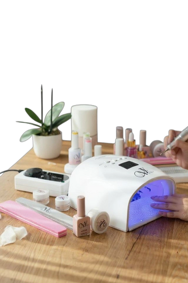 Woman getting a manicure with nail polish dryer and tools on table.