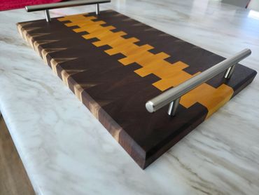 An end grain charcuterie board made from black walnut and yellow heart with serving handles.
