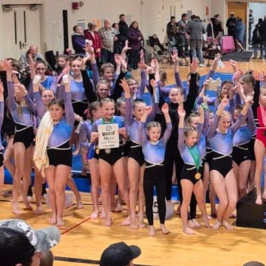 Gymnastics team celebrating with a first-place award.