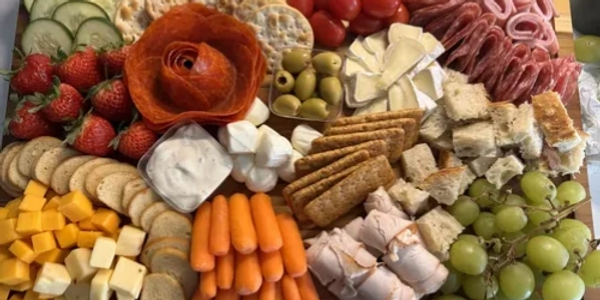 Variety charcuterie board with meats, cheeses, fruits, and crackers.