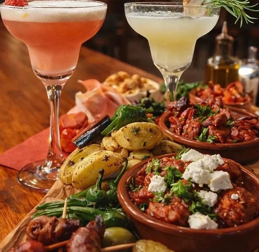 Hier ist die Tapas Platte für zwei zu sehen und zwei unserer Signature Drinks. Dianas und Annas.