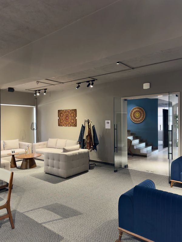 Modern living room with neutral sofas, blue armchairs, and decorative wall art.