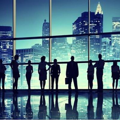 Silhouettes of businesspeople against a city skyline through large windows.